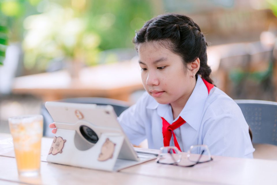 Ảnh minh họa: học sinh mặc đồng phục, quàng khăn đỏ học trực tuyến ngoài trời